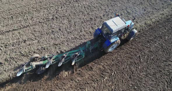 Tractor with a Trailed Plow Cultivating the Soil in Season