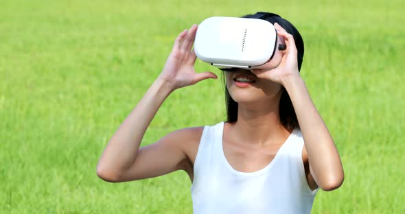 Woman watching with virtual reality device and sitting at the park 