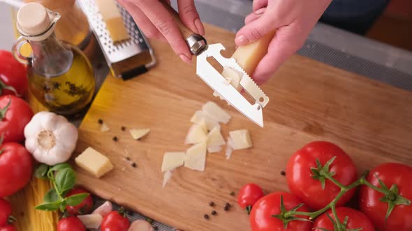 Slicing Italian Parmesan Cheese Over Wooden Cutting Board at Domestic Kitchen