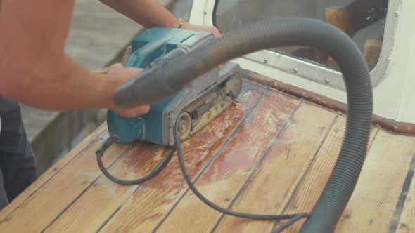 Belt sanding roof planks of wood boat using belt sander. MEDIUM SHOT