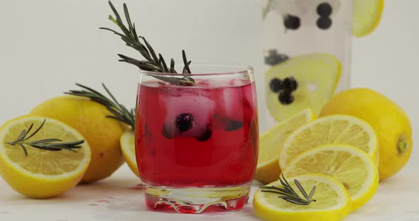 Adding Lemon Slice, Rosemary, Straw in a Glass with Soda Lemonade Red Cocktail