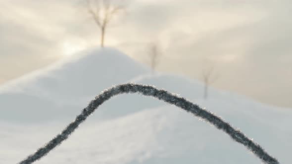 Frosted Wire Fence Covered With Ice Crystals In Front Of Snow Covered Hills