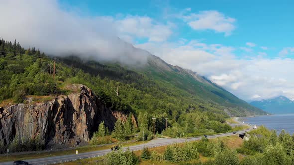 4K Drone Video of Cars Travelling on Seward Highway at Base of Mountain Along Shoreline of Turnagain