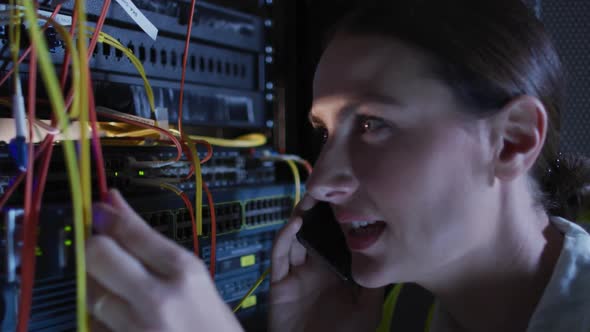 Caucasian female it technician using smartphone checking computer server