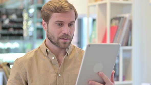 Portrait of Celebrating Success on Tablet By Young Man 