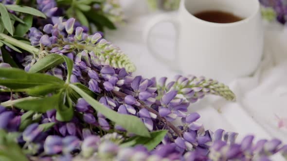 Spring Composition with Flowers and a Cup of Tea on a White Sheet. Flowers and a Cup of Coffee Among