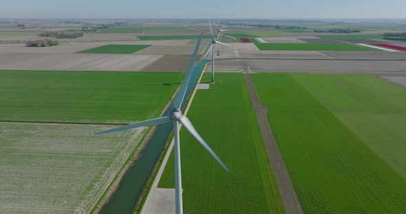 Wind turbines spinning and generating clean energy in Holland, with classic water canal crossing fla