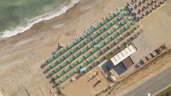 Spiral Flight Over the Hotel's Tourist Beach with Sunbeds and Awnings