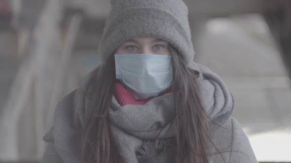 S-log 2. Portrait of Brunette Grey-eyed Girl in Winter Clothes and Protective Mask Looking at Camera