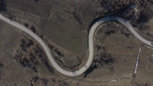 Ascending over the serpentine road with vehicles moving slowly 4K drone video