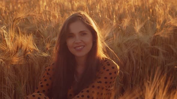 Pregnant woman in the rays of the sunset in the field