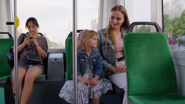 Family Rides in Public Transport Woman with Little Child Girl Sit Together and Look Out Window Tram