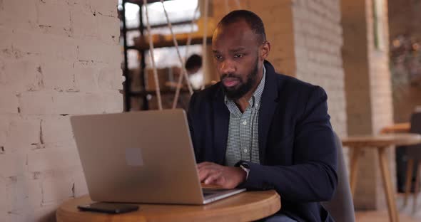 African Businessman Works By Laptop PC in Cafe