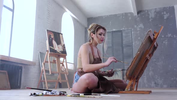 Female Artist Painting Picture in Studio Sitting on the Floor