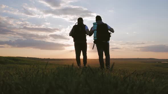 The Silhouette of Two Man on the Top of Mountain with Backpacks and Other Gear Expressing Energy and