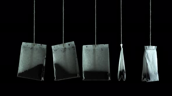 Set of New Tea Bags with Tasty Brew Hang on Black Background