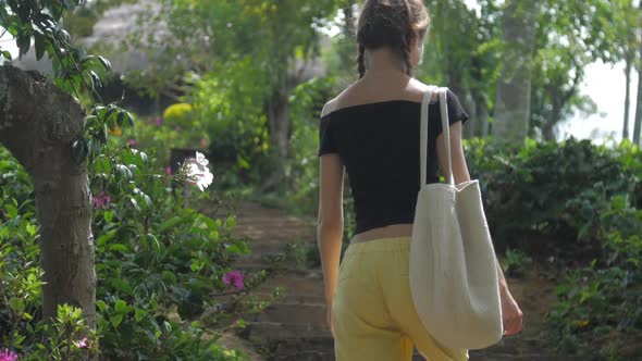 Young Woman in Yellow and Black Dressing Turns and Walks