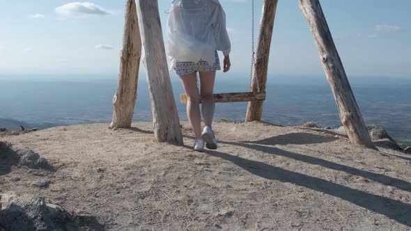 Back view of woman on wooden swing enjoying view from top of Folgosinho mount in Portugal. Tilt-up