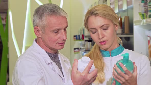 Two Chemists Discussing Products on Sale at Their Drugstore