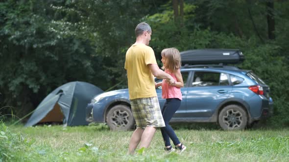 Young Father and His Child Daughter Dancing Having Fun Outdoors at Camping Site in Summer