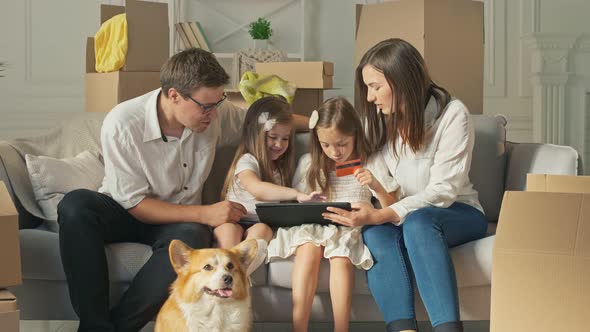 A Happy Family Uses a Tablet for Online Shopping, Sitting on the Couch at Home.