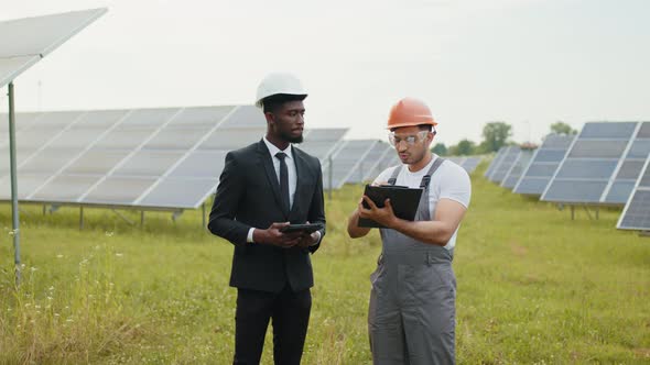 Owner and Worker Signing Papers Among Solar Cells Outdoors