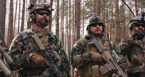 Squad of Fully Equipped Soldiers in Camouflage Stand in Dense Pine Forest Reconnaissance Military