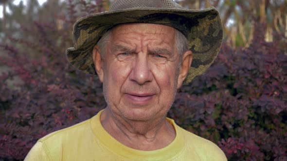 Portrait Of Senior Caucasian Man In A Hat On The Street In Looking At Camera