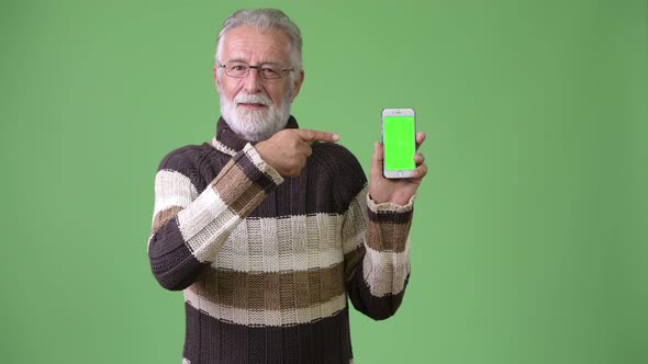 Handsome Senior Bearded Man Wearing Warm Clothing Against Green Background