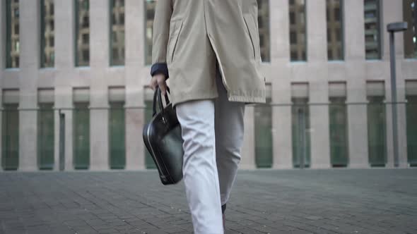 Young Trendy Businessman Walking in a Modern Corporate Business District Carrying Leather Briefcase
