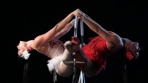 Two Woman in Makes Graceful Element in the Aerial Hoop. Black Background. Slow Motion. Close Up