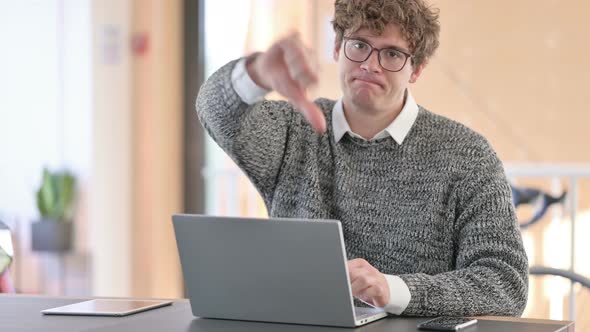 Young Young Man with Laptop Showing Thumbs Down 