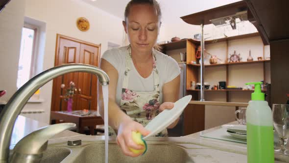 woman washes dishes in kitchen