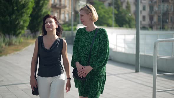 Two Confident Adult Women Walking in City Talking in Slow Motion Laughing