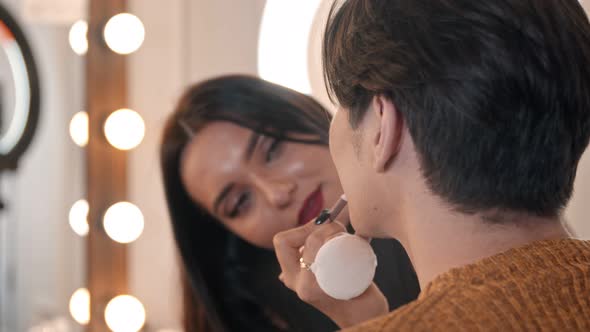 Woman Make Up Artist Applying a Brown Pencil on the Lips of Male Model