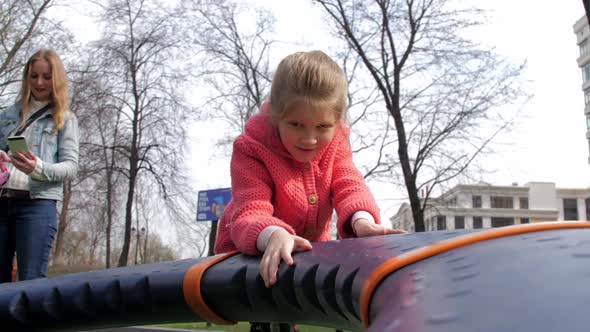 Delighted Schoolgirl Plays on Playground Attraction in Park