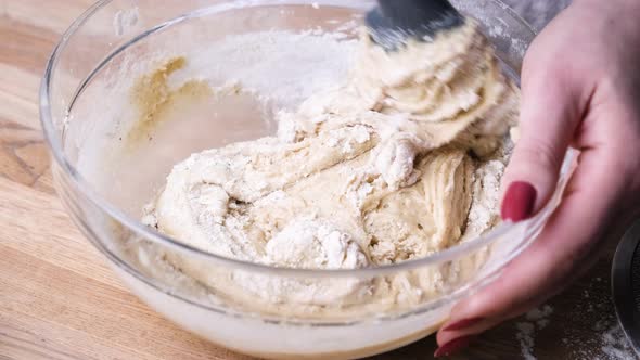 Hands Mixing Cake Batter with a Spatula in a Glass Bowl. - Slider Left