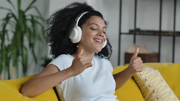 Portrait of a Young African American Woman Enjoys Music with Big White Headphones