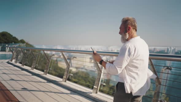 Cheerful Senior Man Enjoys Music on Smartphone Dancing