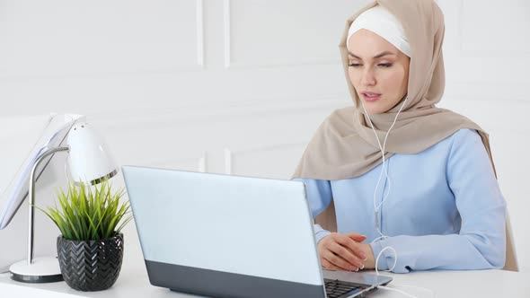 Muslim Woman Is Learning English in Earphones Online Using Computer