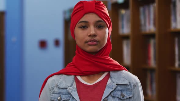 Portrait of a smiling Asian female student wearing a red hijab and looking at camera