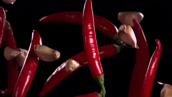Super Slow Motion Shot of Flying Red Chilli Peppers and Garlic