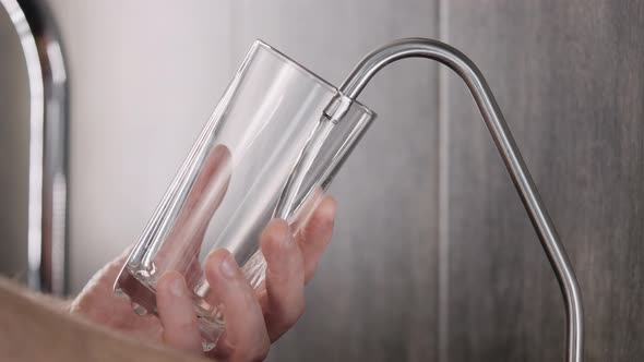 A Man Collects Drinking Water in the Kitchen