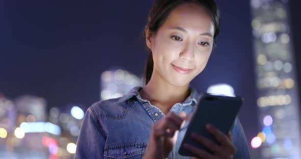 Asian woman use of mobile phone in the city at night 