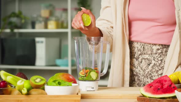 Woman Squeezing Half of Lime Into Blender Closeup Cooking Detox Smoothie Made of Citrus Fruits and