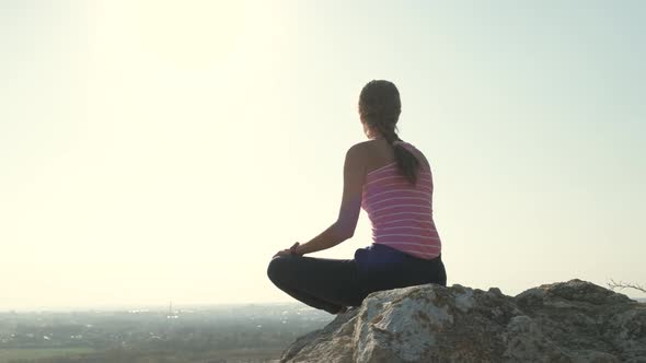 Young Relaxed Woman Sitting Outdoors on a Big Stone Enjoying Warm Summer Day