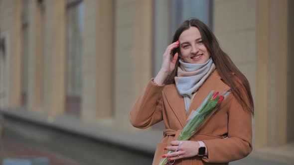 Portrait of a Happy Girl with a Tulip on the City Street