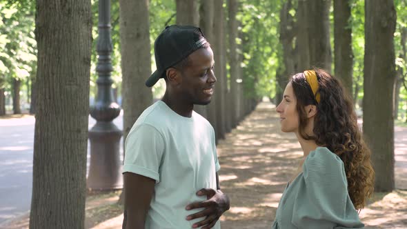 AfroAmerican Man in Cap Talks to Brunette Woman Laughing