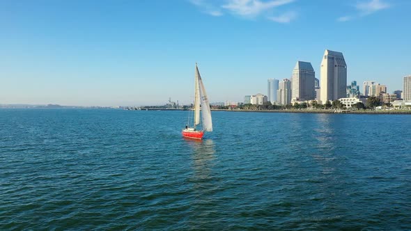 Red sailboat on the San Diego Bay with a view of San Diego's skyline