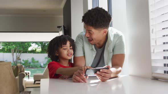 Happy biracial man and his son using smartphone together